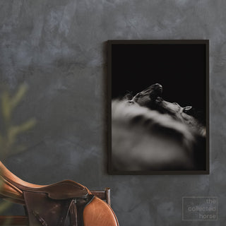 Black and white equestrian fine art print of two horses playing by Carolin Felgner - framed wall art mockup with saddle