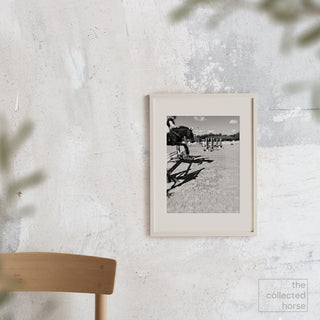 Black and white equine photography art print of a horse jumping over an oxer by Morgan German - framed giclée art print on wall mockup 2